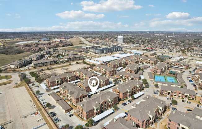 An aerial view of a residential area with a swimming pool and a tall building in the distance.