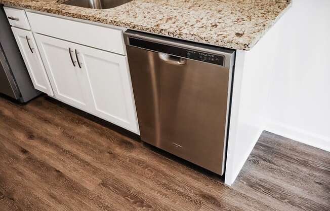 a stainless steel dishwasher in a kitchen with white cabinets