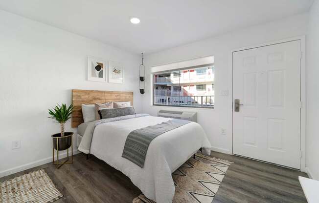 A bedroom with a bed, nightstand, and a window overlooking a street.