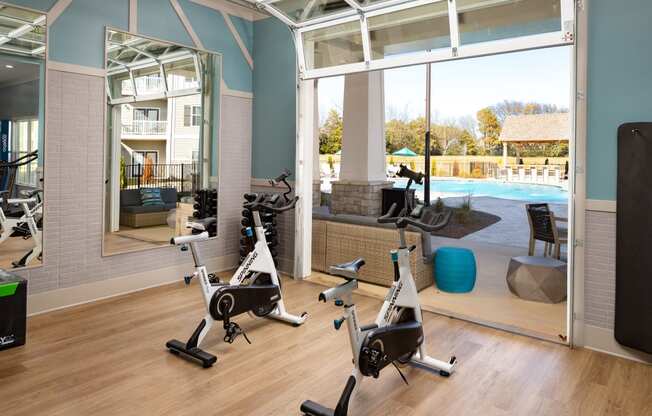 Premium fitness center with exercise machines, wood-designed flooring, wide windows, and high ceiling at The Alexandria