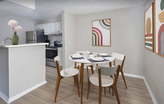 a dining area with a table and chairs and a kitchen in the background