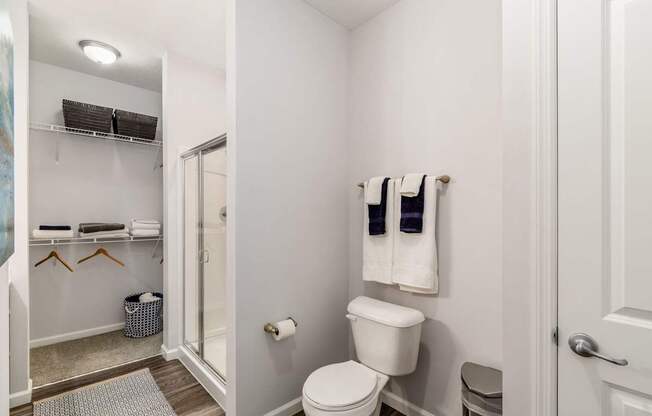 A white bathroom with a toilet, towel rack, and a mirror.