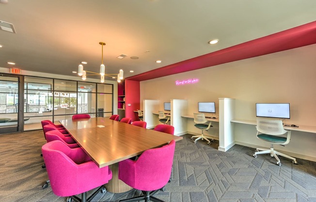 a conference room with a wooden table and pink chairs at Pinnacle Apartments, Jacksonville, Florida