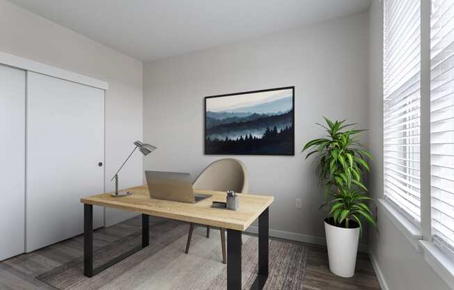close up of a desk with a laptop and a painting of a mountain