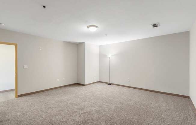 the living room of an empty apartment with carpet and a lamp