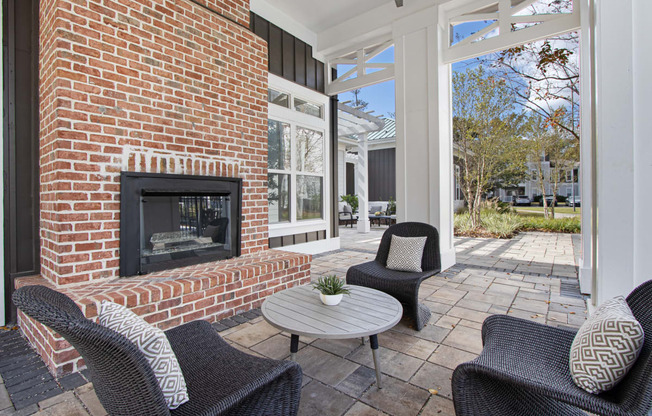 a patio with chairs and a brick fireplace