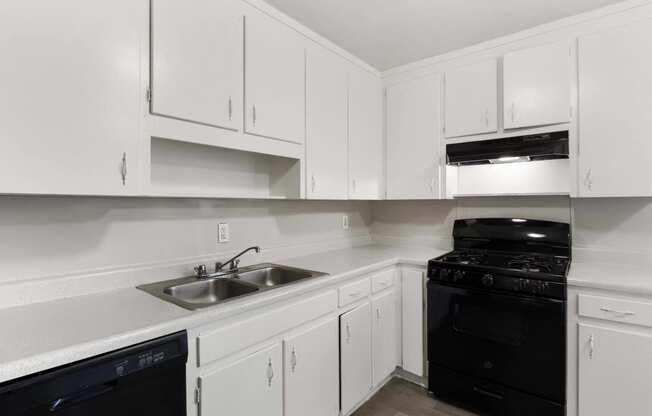 an empty kitchen with white cabinets and black appliances