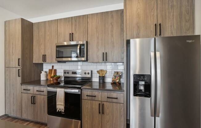 a kitchen with stainless steel appliances and wooden cabinets at Stella, San Tan Valley, AZ 85143