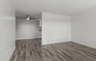 an empty living room with wood flooring and a ceiling fan