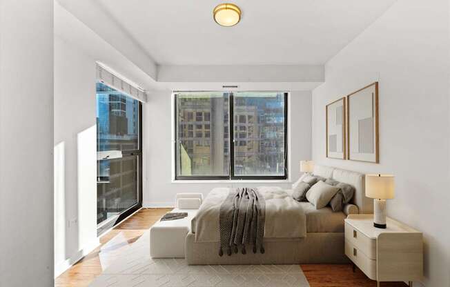 A bedroom with a large bed and a window overlooking a cityscape.