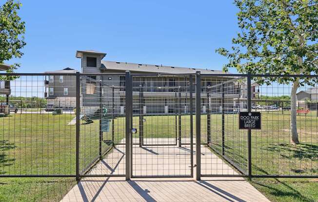 A black metal gate with a sign that reads "DOG PARK BREAK" in front of a building.