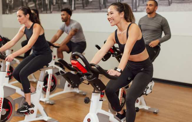 a group of people cycling on an exercise bike in a gym