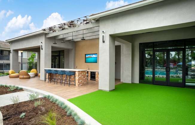 a patio with a bar and green grass in front of a house