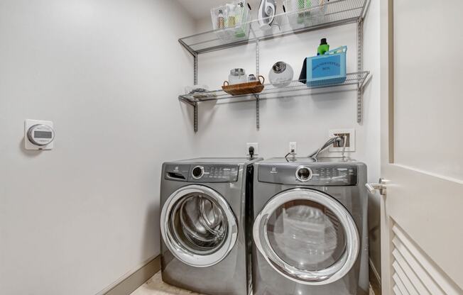 a washer and dryer in a laundry room with a wall mounted shelf above