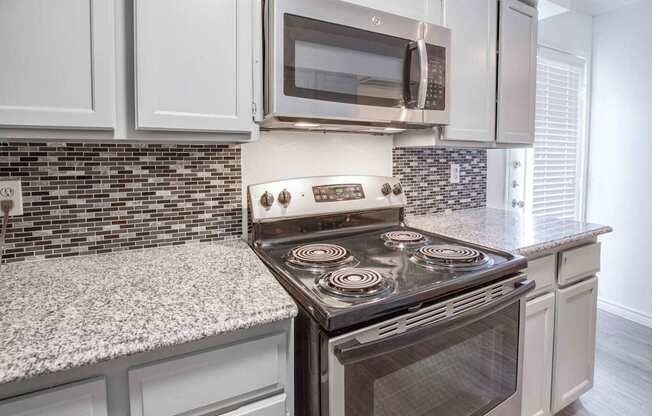 A modern kitchen with a stove top oven and microwave above it.
