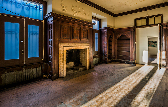 Before: Cigar lounge with wood-burning fireplace surrounded by wood paneled walls and built-in bookshelves