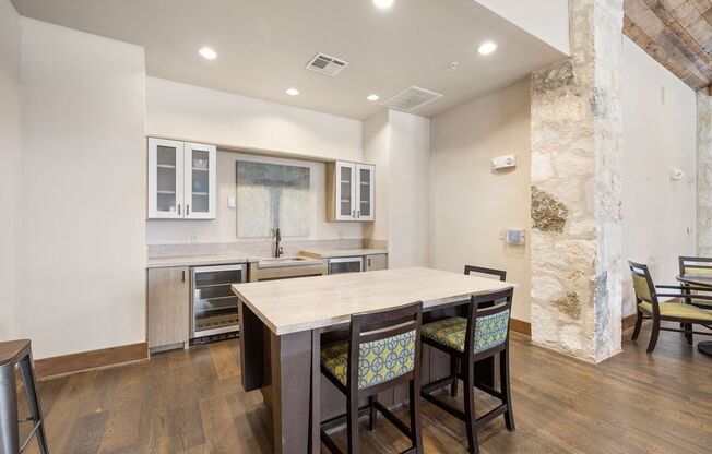 a kitchen with a large island with four chairs in front of it at Lakeline East Apartments, Cedar Park, TX