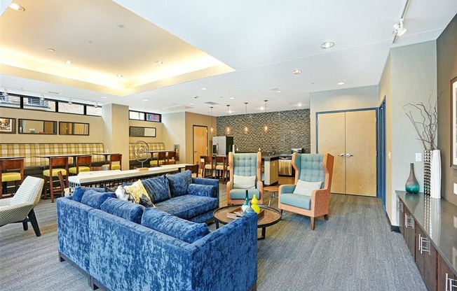 A blue velvet couch sits in a well-lit room with a wooden table and chairs.