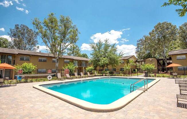 a swimming pool with trees and apartments in the background