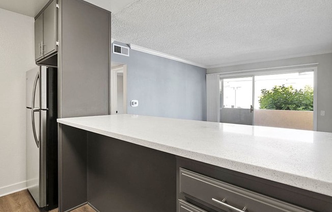 White tiled kitchen with bar seating facing hardwood floored living room.