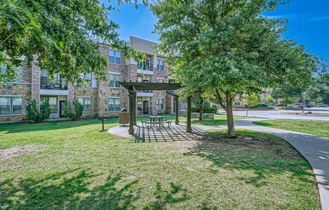 a park with trees and a picnic area in front of a building at Discovery at Craig Ranch, Texas, 75070