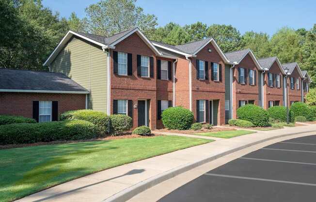 A row of red brick houses with green lawns in front.