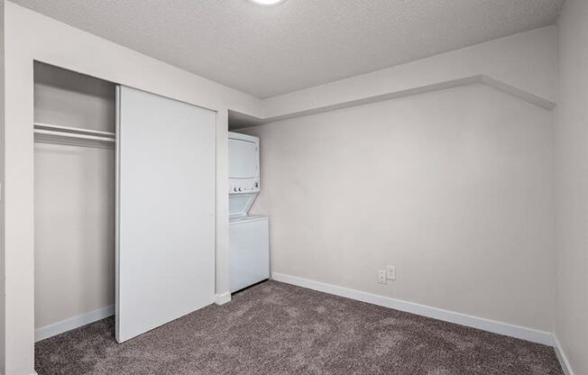 a bedroom with a closet and a washer and dryer