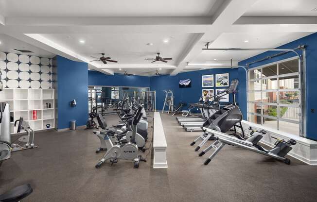 a gym with treadmills and other exercise equipment in a building with blue walls