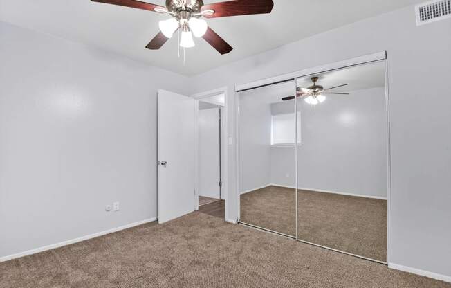 carpeted room with large closet and ceiling fan