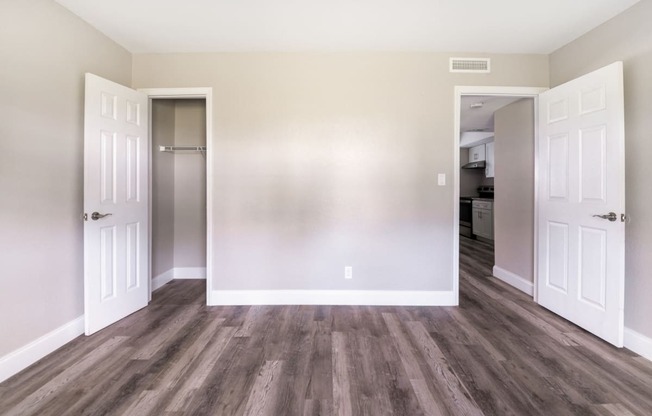 an empty room with wooden floors and white doors