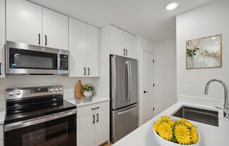 A modern kitchen with white cabinets and stainless steel appliances.