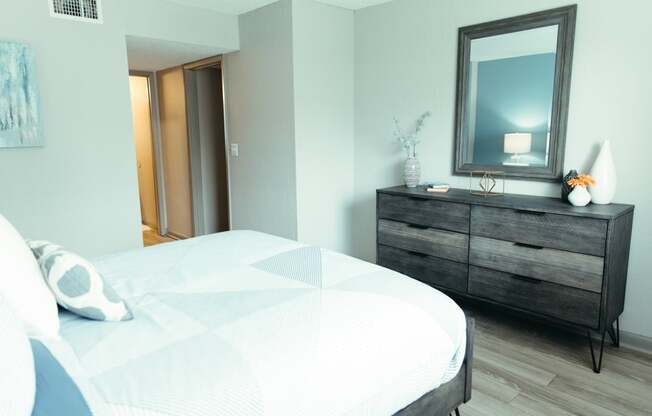 a bedroom with a bed and a dresser with a mirror