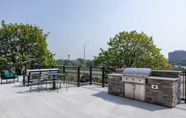 A BBQ grill is on a patio with a table and chairs.