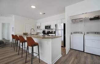 A kitchen with white appliances and brown bar stools.