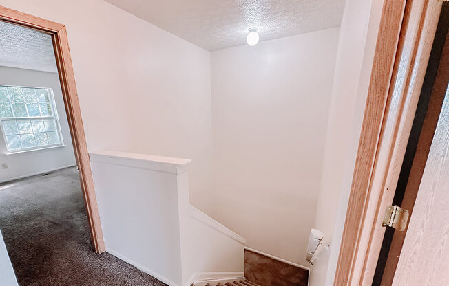 a doorway into a room with a staircase and a window