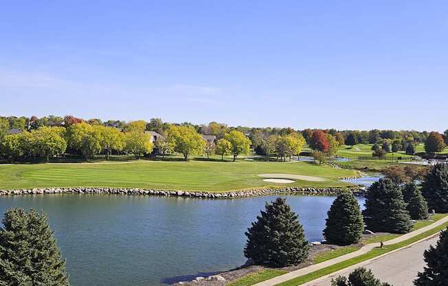 a view of a golf course and a pond surrounded by trees