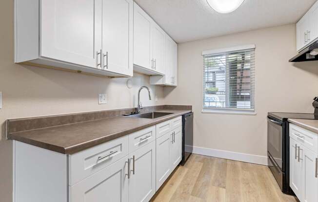 A kitchen with white cabinets and a brown countertop.