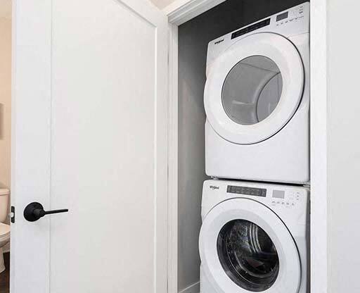 A white door opens to a small laundry room with a washer and dryer.