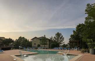 a pool with chairs around it and a house in the background
