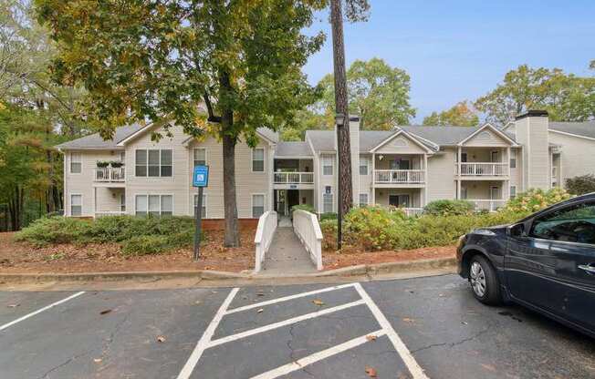 A car is parked in a parking lot in front of apartment buildings.