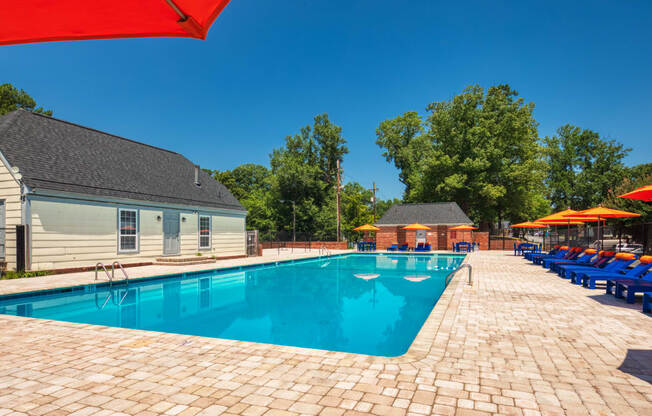 our resort style swimming pool is surrounded by lounge chairs and umbrellas