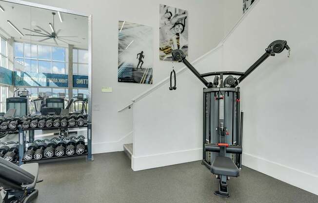 A gym with a weightlifting machine in the foreground.
