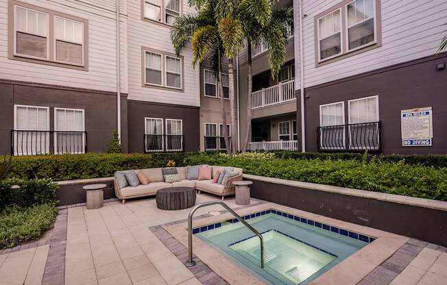 A pool surrounded by a patio and a building.