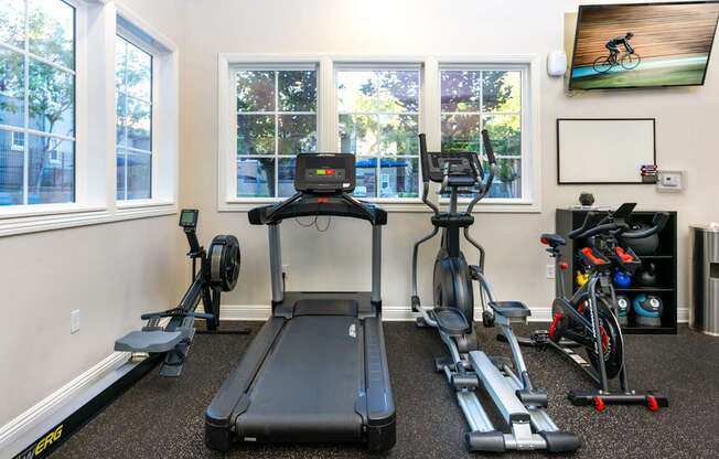 A home gym with a treadmill, exercise bike, and other equipment.