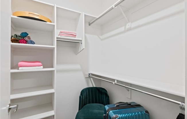 a walk in closet with luggage and chairs