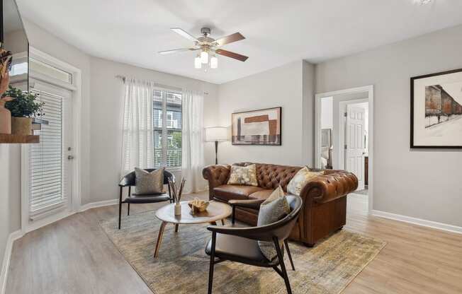 spacious living room with a lighted-ceiling fan and expansive windows at Sorelle apartments