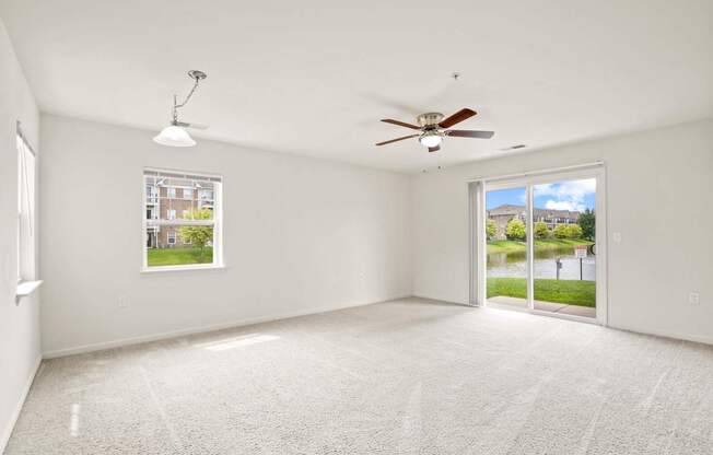 A spacious room with a ceiling fan and a view of the outdoors through a sliding glass door.
