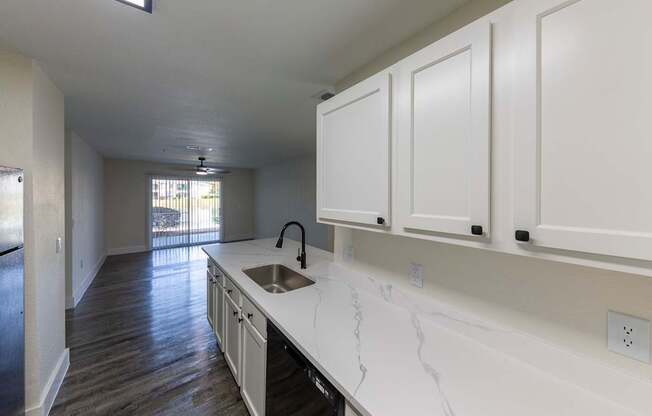 A kitchen with white cabinets and a marble countertop.