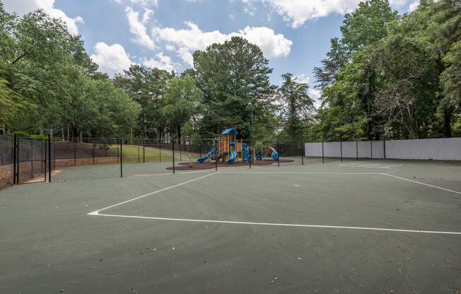 the tennis court is equipped with a playground and a swing set