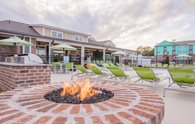 an outdoor patio with a fire pit and green chairs